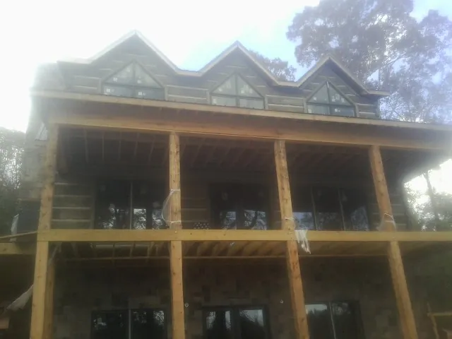 Dormers and porch framing on a large log home under construction — Roof Coating work by our crew in Gwinner