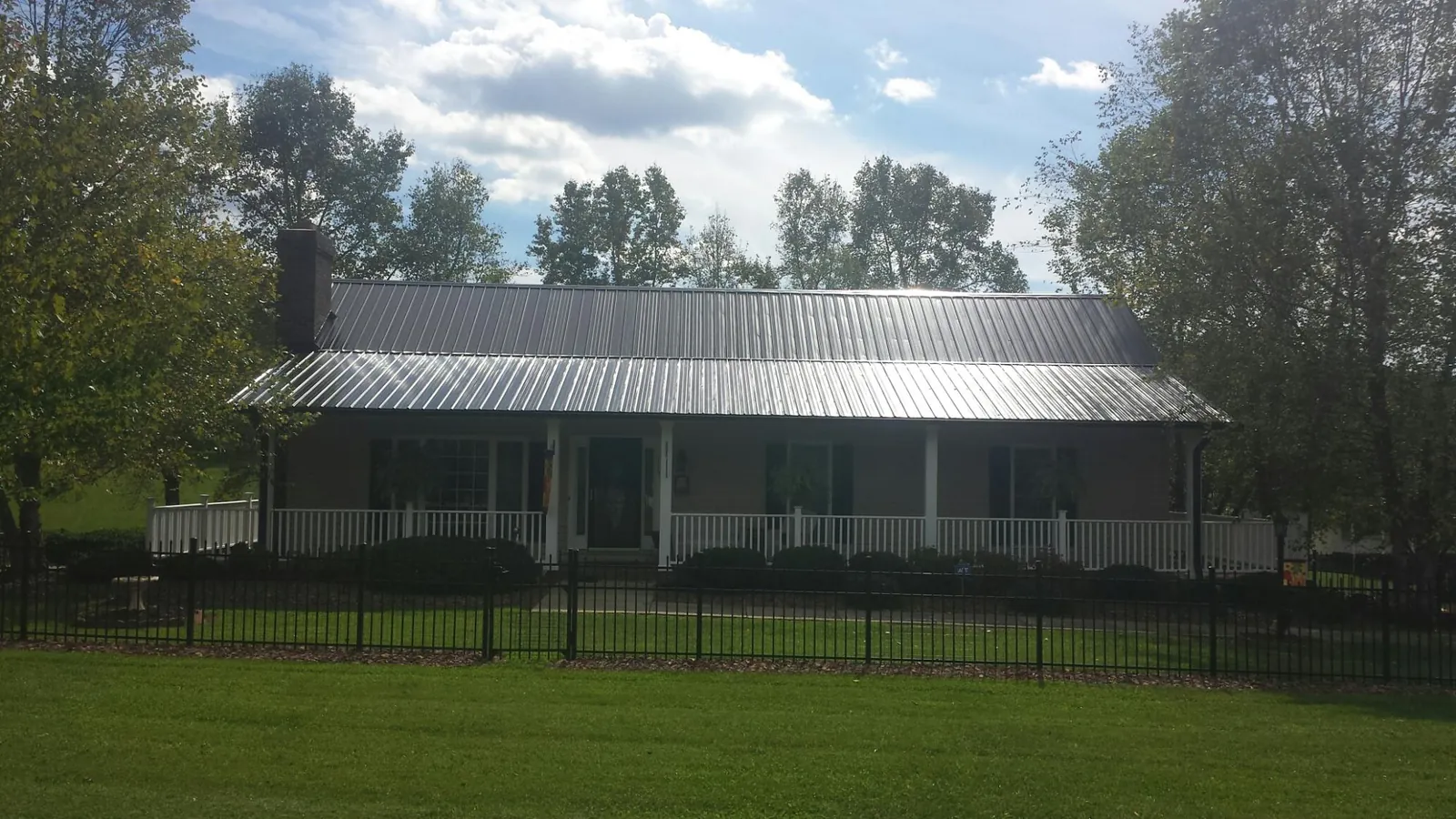 Gray metal roof on a brick ranch with a full width front porch — Gutter Guard Installation work by our crew in Gwinner