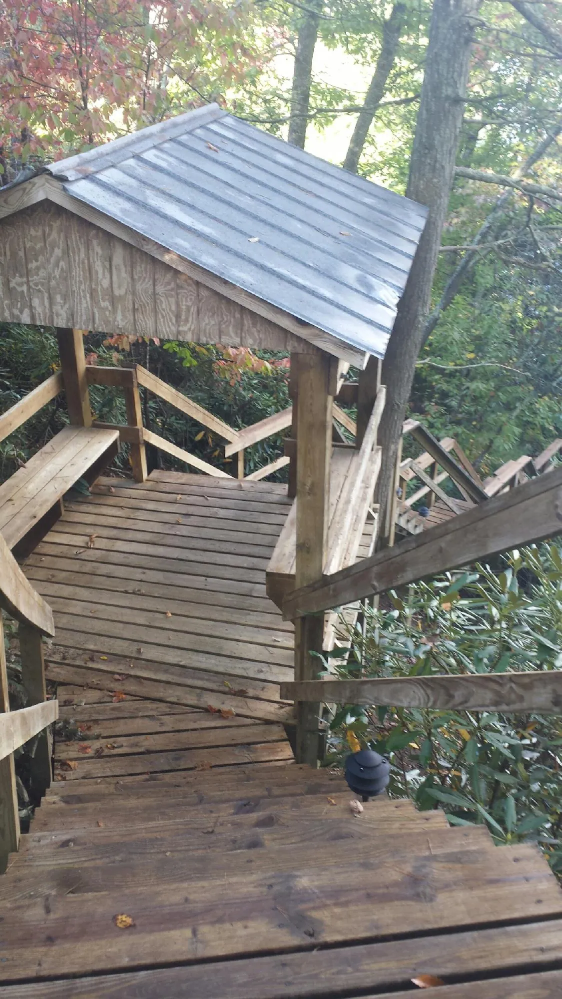 Metal roofed shelter over wooden steps on a wooded walkway — Skylight Repair & Installation work by our crew in Gwinner