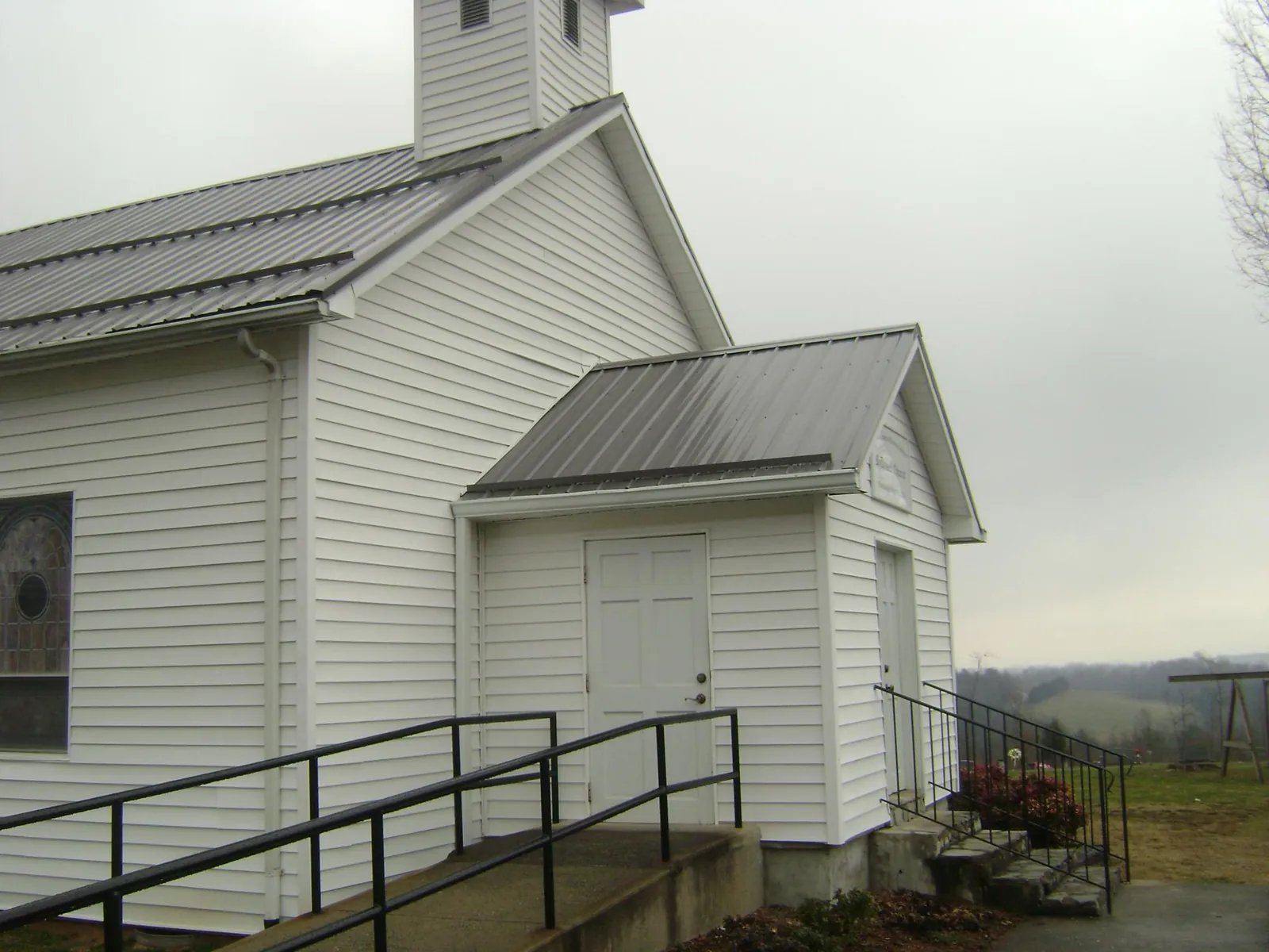 Gray metal roof on a white clapboard church with a steeple in Gwinner