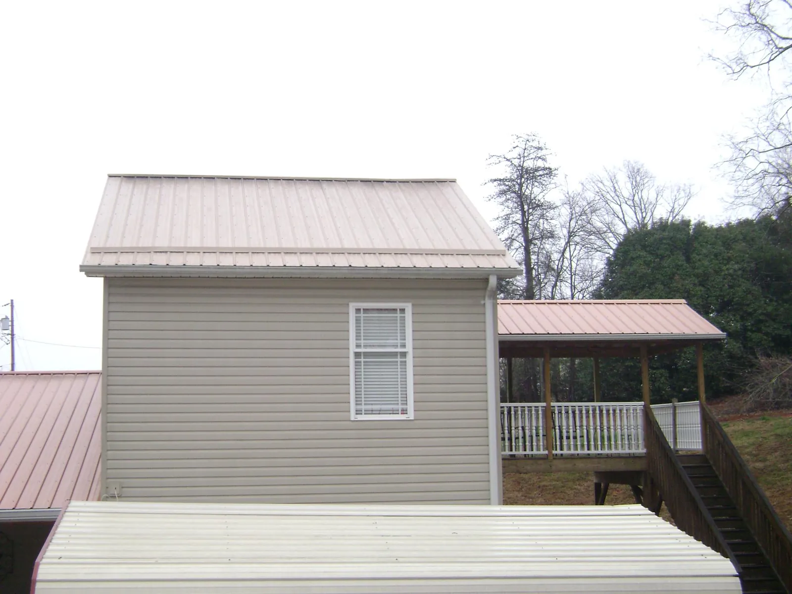 Tan metal roofs on a two story addition and attached porch, from a Roof Replacement job in Gwinner