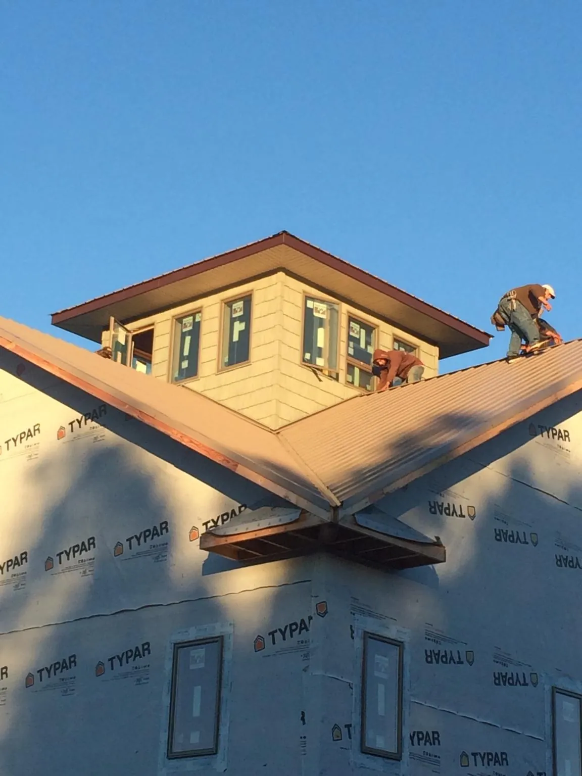 Roofers working around a rooftop cupola on a new metal roof at sunset — Roof Waterproofing in Gwinner by Roofing Brothers